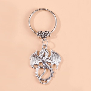 Retro silver dragon keychain pendant with detailed scales and wings on beige background