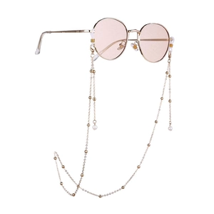 Detail of pink round sunglasses with elegant gold chain and white pearl tassel accents