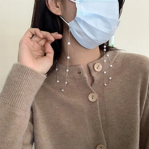 Detail einer Maskenkette mit weißen Perlen und Herzanhängern an einem Damenmodell