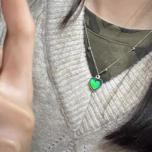Gros plan du pendentif cœur changeant de couleur sur une chaîne perlée en argent sur pull
