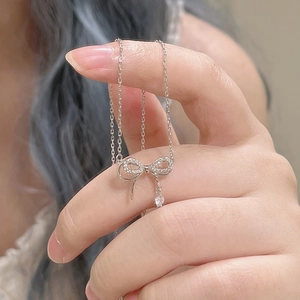 Gros plan d'un pendentif nœud en argent serti de zircones sur une fine chaîne élégante