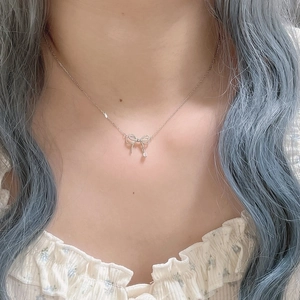 Gros plan d'un collier argenté avec pendentif nœud serti de strass brillants