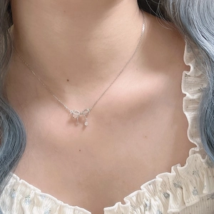 Gros plan d'un collier nœud argenté avec un brillant zircon sur le cou d'une femme