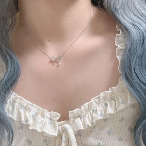 Détail du collier pendentif nœud en argent avec zircon étincelant sur un cou de femme