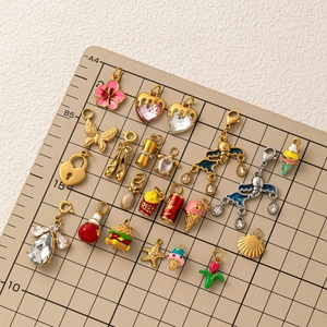 Mix of 18K gold plated heart and food charms on a brown measuring mat with 45-degree angle view