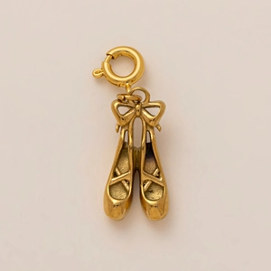Macro view of golden ballet slipper pendant with delicate bow and spring clasp closure