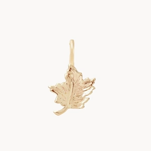 Vista macro de un colgante de hoja de arce bañado en oro 14K con texturas finas