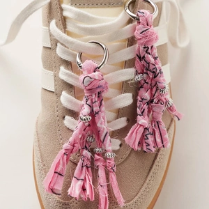 Close-up of pink fabric tassel shoe charms with silver beads on suede sneakers