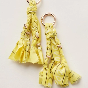 Close-up of handmade bright yellow braided fabric keychains with rose gold metal rings