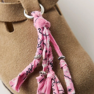 Detail of pink printed fabric charm with silver beads on brown suede footwear