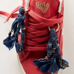 Red high-top canvas sneaker featuring handmade bohemian woven charms and metal details