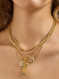 Détail de colliers superposés plaqués or avec pendentifs caméra, avion et Sophia