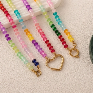 Detail of colorful beaded necklaces featuring golden heart-shaped and round spring clasps