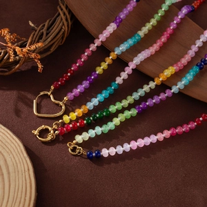 Detailed close-up of colorful beaded necklaces with golden heart clasps on a rustic background