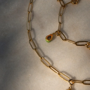 Gros plan du collier trombone plaqué or 18 carats avec un pendentif papaye en émail coloré