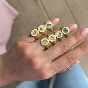 Set of seven gold enamel signet rings with lion and heart designs on woman's hand