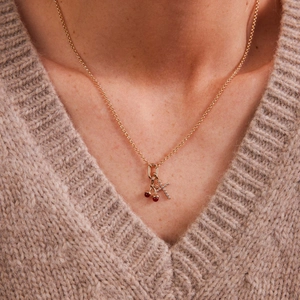 Gros plan d'un collier plaqué or 18 carats avec pendentifs cerise et lettre K en cristal
