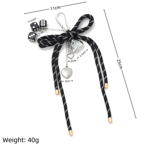 Detailed view of DIY bag charm with black and white bow, dice, and metal heart pendants