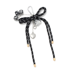 Bow keychain with black dice, silver rose and heart charms on a white background