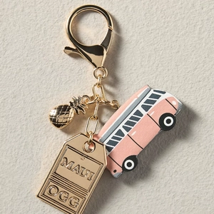 Detail of vintage bus keychain with golden pineapple charm and engraved metal tag