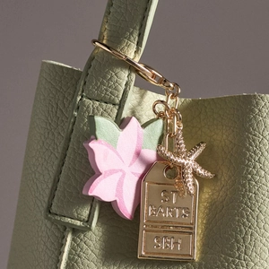 Close-up of golden starfish and ST BARTS engraved charm on a textured leather handbag