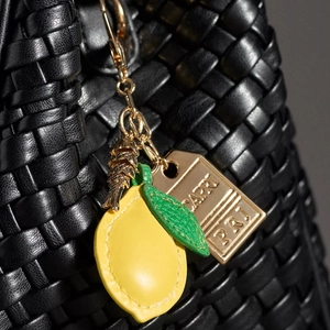 Black woven handbag with a yellow lemon leather charm and gold Capri logo tag