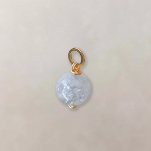 Macro shot of a light blue gemstone pendant with golden wire wrap and polished metal clasp
