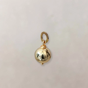 Macro shot of gold spherical pendant with polished mirror finish and wire-wrap detail