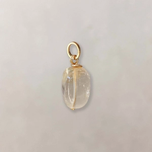 Detail of a natural yellow stone pendant with gold-plated wire-wrapped bail and smooth finish