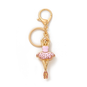 Détail du porte-clés ballerine dorée avec strass roses et robe en émail sur fond blanc