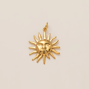 Vue macro d'un pendentif soleil céleste plaqué or 18K avec rayons sur fond beige doux