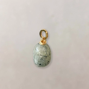 Detailed macro of oval green natural stone pendant with gold wire wrap and large ring