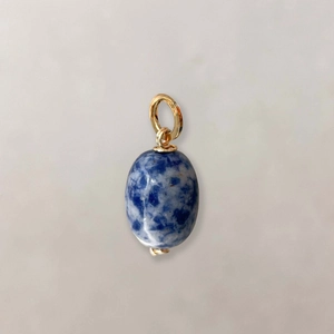 Detail of oval blue natural stone pendant with gold-plated hook and marble texture