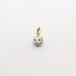 Close-up of a detailed cat pendant with 18K gold finish and blue eyes on a white background