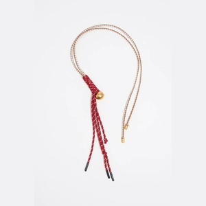 Détail du pendentif en corde tressée rouge et blanc avec sphère et accents dorés