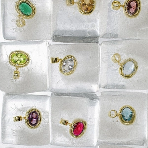 Detailed view of nine colorful oval gemstone pendants displayed on ice cubes