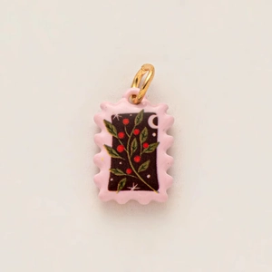 Detail of a black enamel stamp pendant with pink berry motif and gold plated loop