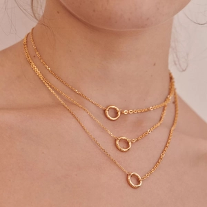 Close-up of triple-layered gold necklaces with circular pendants on female model