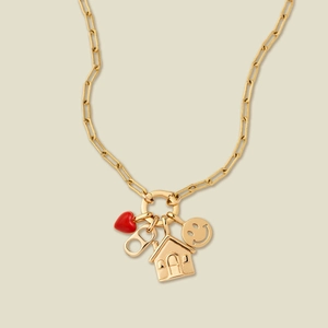 Detail of gold paperclip chain necklace with heart, house, and smiley face charms