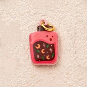 Close-up of pink magic potion bottle pendant with moon and star pattern in 14K gold