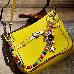 Colorful beaded bag charm with metal mushroom and star pendants on a yellow handbag