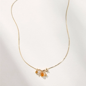 Detail of 14k gold plated necklace featuring square orange and teardrop crystal pendants