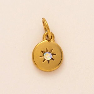 Detailed view of a gold starburst pendant with a rainbow rhinestone and engraving
