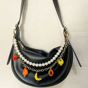 Détail d'un sac demi-lune noir avec bandoulière perles et breloques fruits colorés