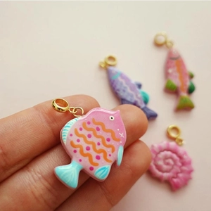Detailed close-up of a pink fish pendant with resin ocean theme and gold metal ring