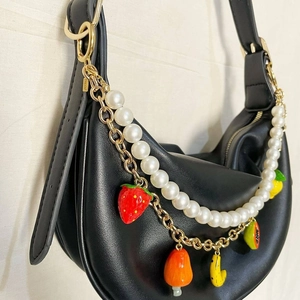 Détail du sac croissant noir avec chaîne de perles et charms de fruits colorés