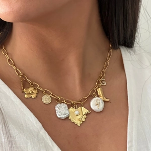 Détail du collier à breloques doré avec perles baroques, motif éclair et pendentifs fleurs