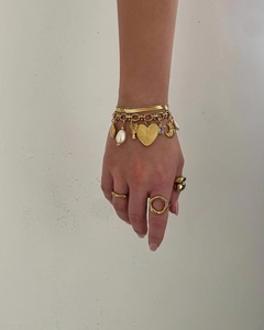 Gros plan de bijoux superposés dorés avec breloques cœur et pendentifs perles