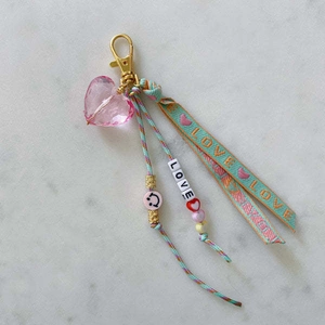 Détail d'un cœur en cristal rose avec ruban LOVE et pendentif porte-clés perlé