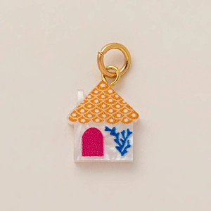 Détail macro du pendentif maison avec finition blanc nacré et motifs de toit colorés